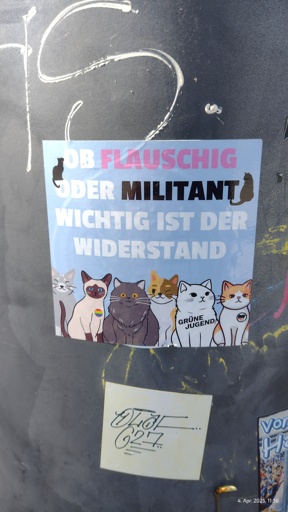 ein Aufkleber mit verschiedenen Katzen im Comic-Stil mit Anstecken der Antifa, GrünenJugend und Pride darüber der Schriftzug "Ob flauschig oder Militant, wichtig ist der Widerstand!"