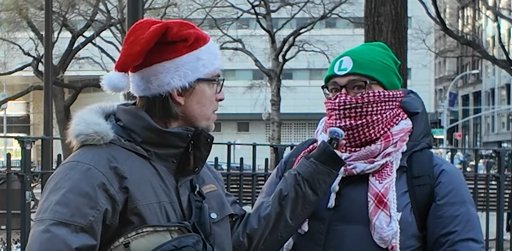 someone in a santa hat interviewing someone wearing a kuffiyeh and a beanie styled in the theme of the Super Mario character Luigi