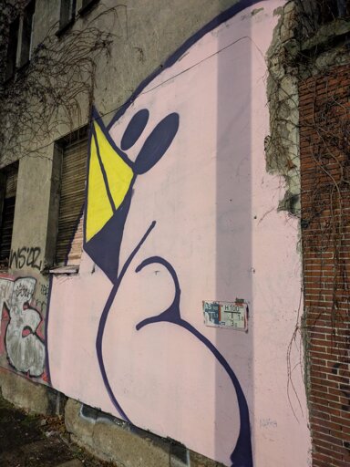 Round stylized white/light grey bird on darker grey wall. Spray painted and probably 4 meters tall