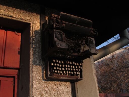 A rusted typewriter hangs above the entrance of a house.